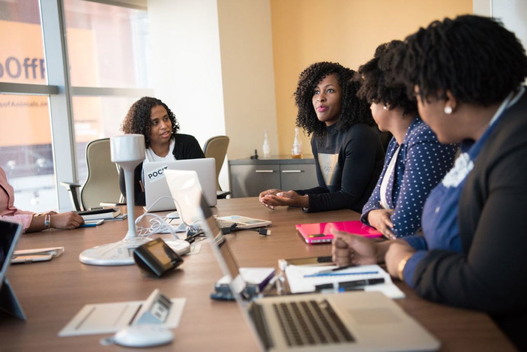 Group of female co-workers around a conference table discussing a project.