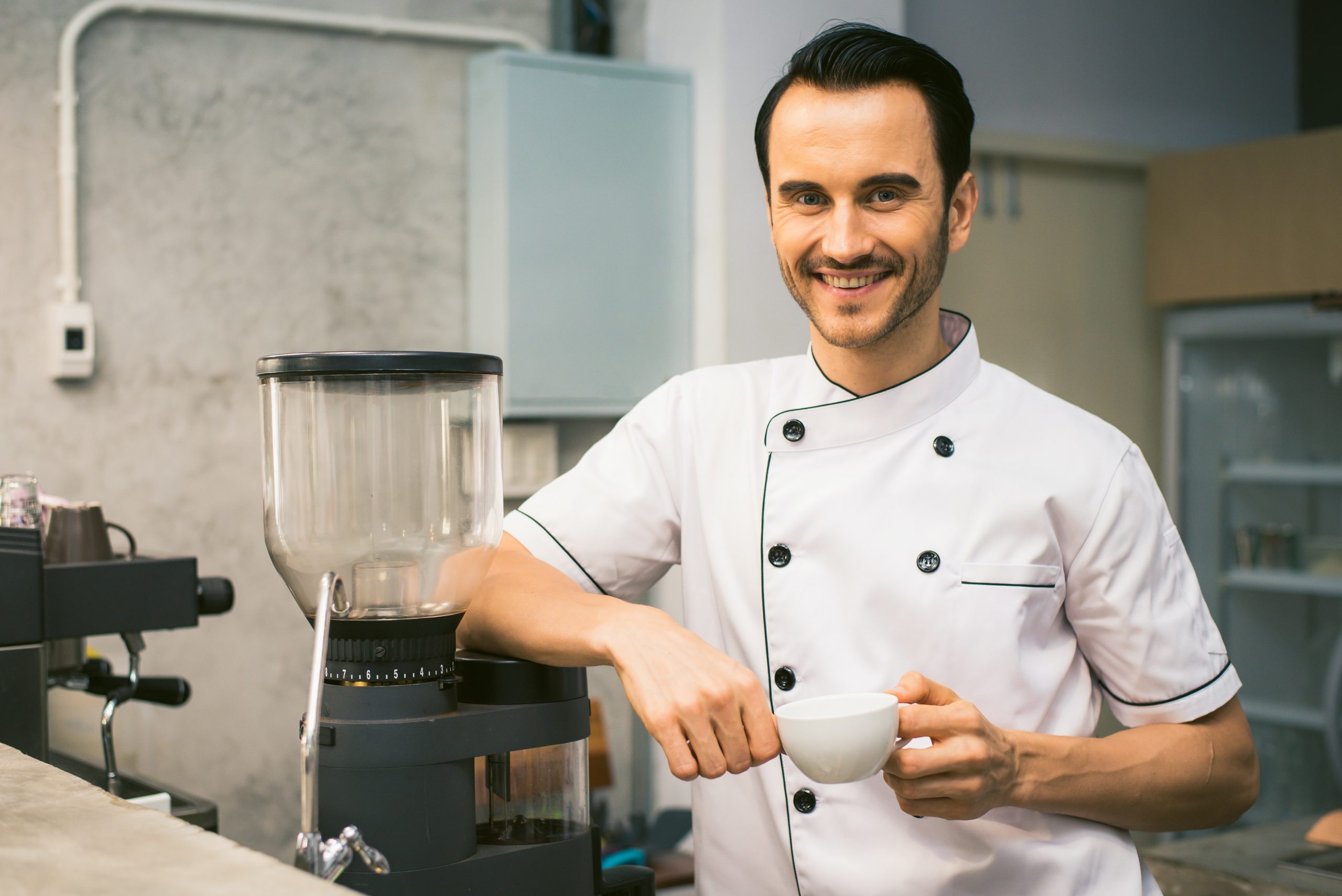 Chef smiling while holding a white tea cup.